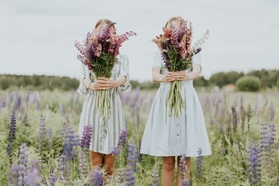 两个女人拿着粉色有花瓣的花
